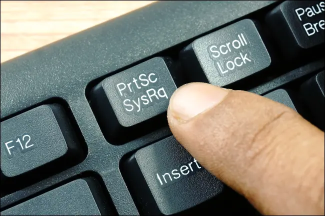 Ein Finger, der die PrtSc-Taste in der obersten Reihe einer PC-Tastatur drückt.