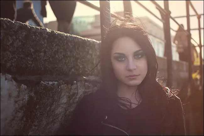 Ritratto di una ragazza con il sole dietro di lei, creando riflesso lente.