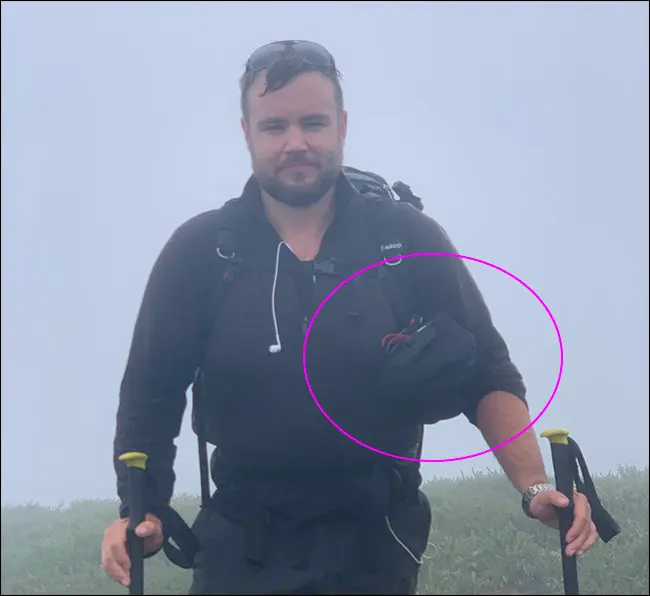 Un hombre camina bajo la lluvia con un trípode y una bolsa Peak Design Camera Shell.