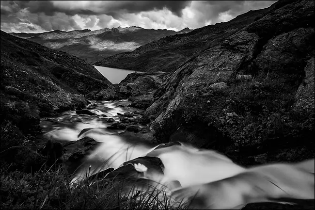 Una foto in bianco e nero di un ruscello in montagna dopo la pioggia.