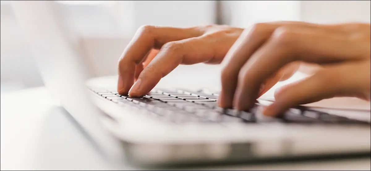 Persona escribiendo en el teclado de una laptop