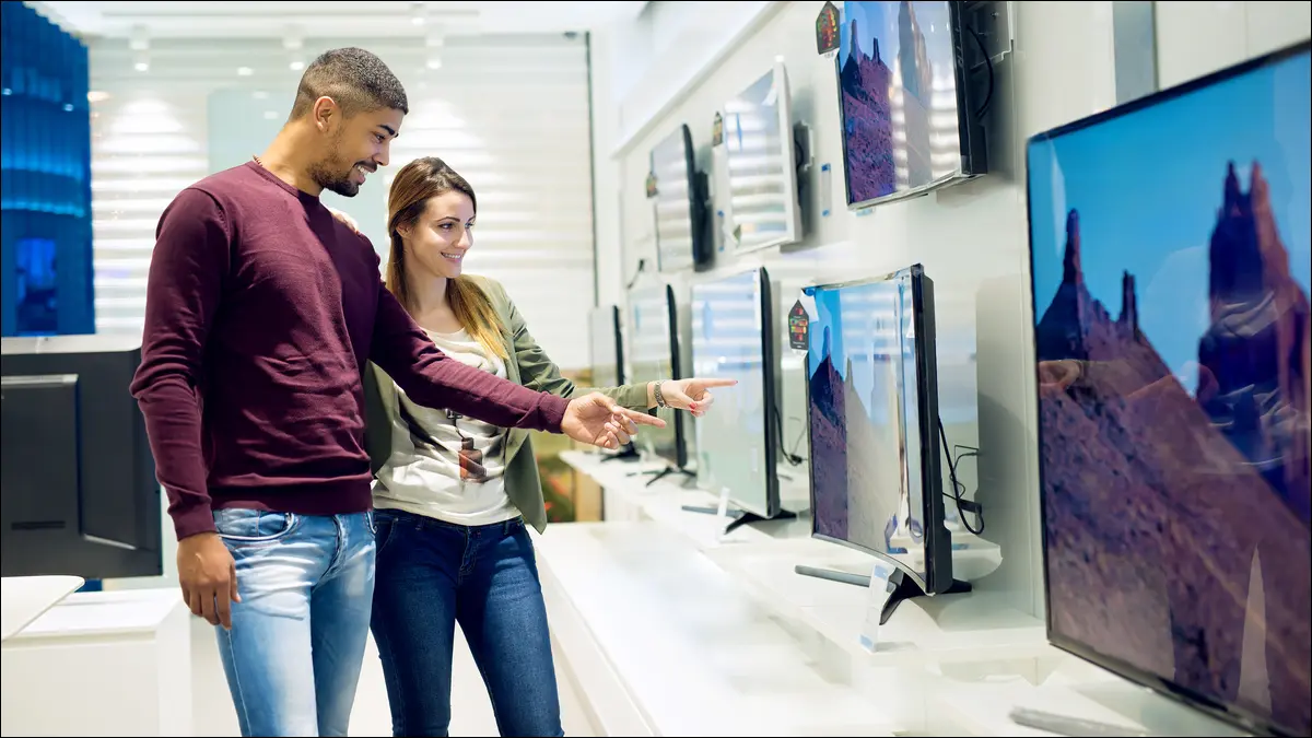 Duas pessoas comprando uma TV em uma loja de eletrônicos