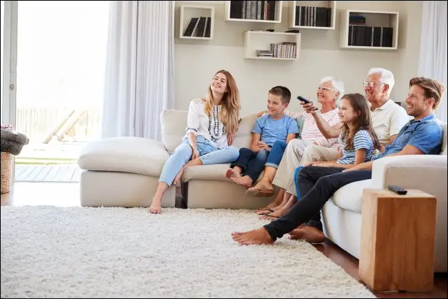 Una famiglia seduta su un divano a guardare la TV.