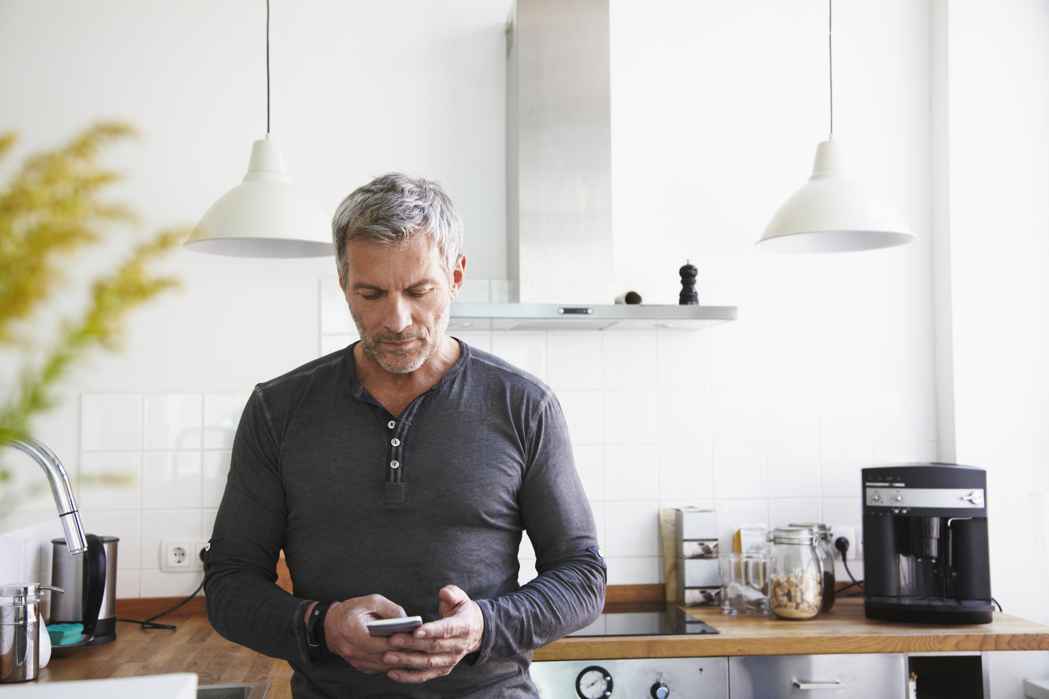 彼の携帯電話を見ている台所に立っている男