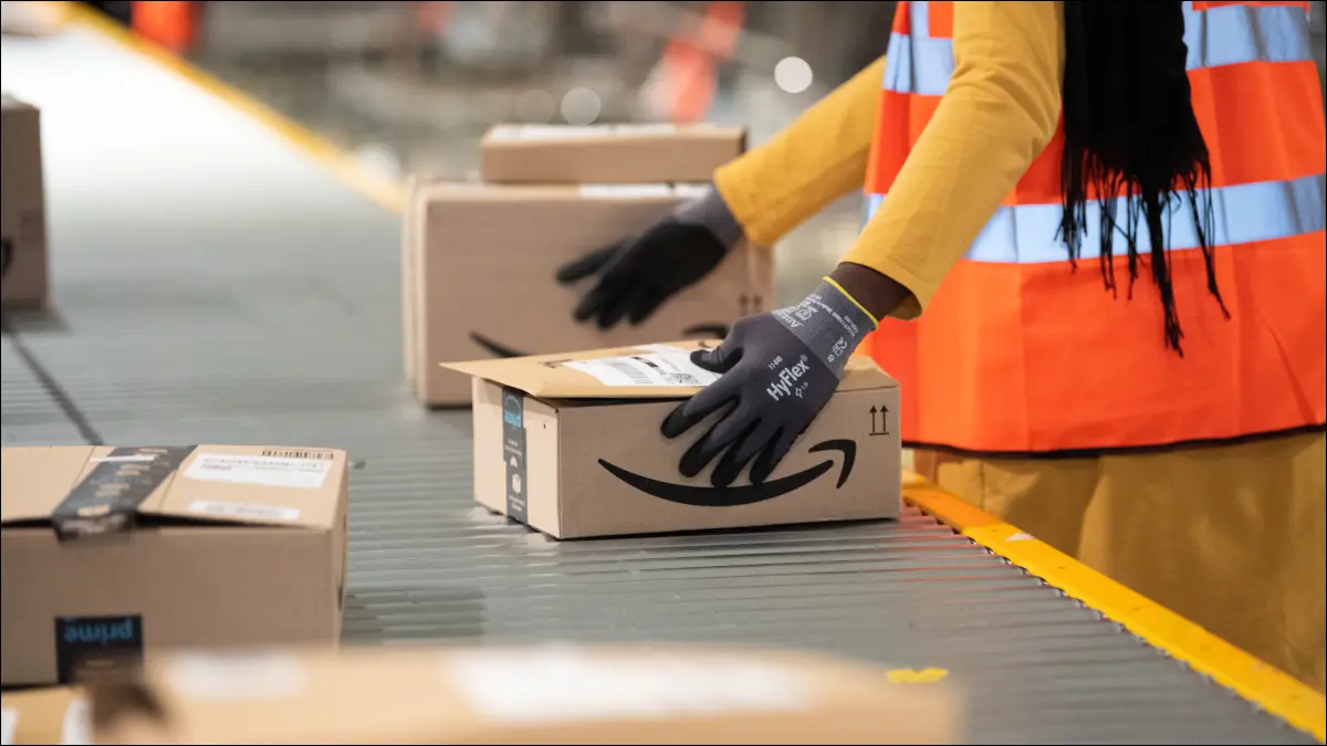 Un dipendente Amazon che gestisce un pacco su un nastro trasportatore.