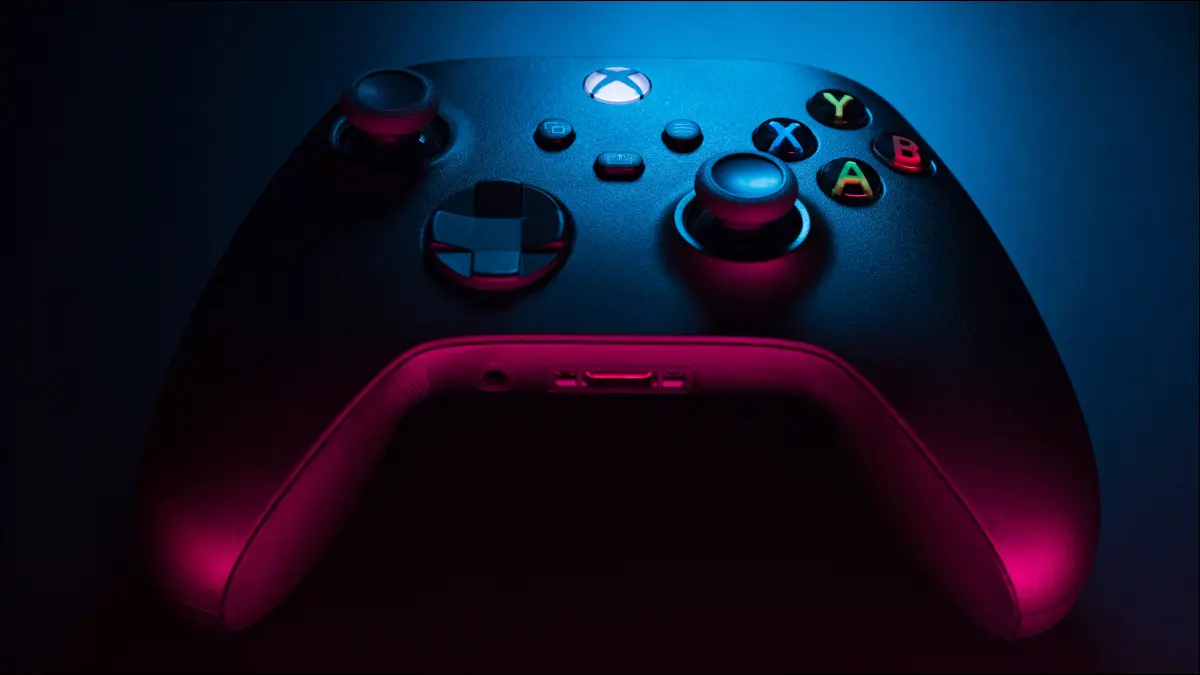 Gros plan d'un contrôleur Xbox Series S noir carbone dans un éclairage bleu et rouge.