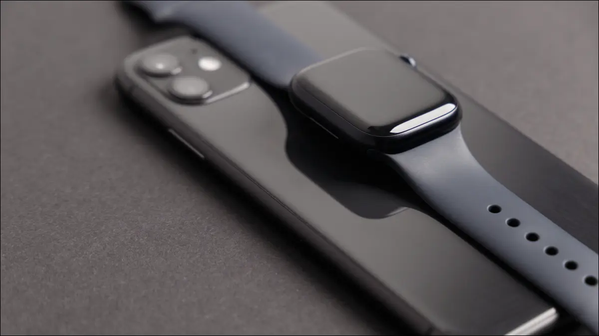 Eine schwarze Apple Watch Series 7 auf einem passenden iPhone 11.