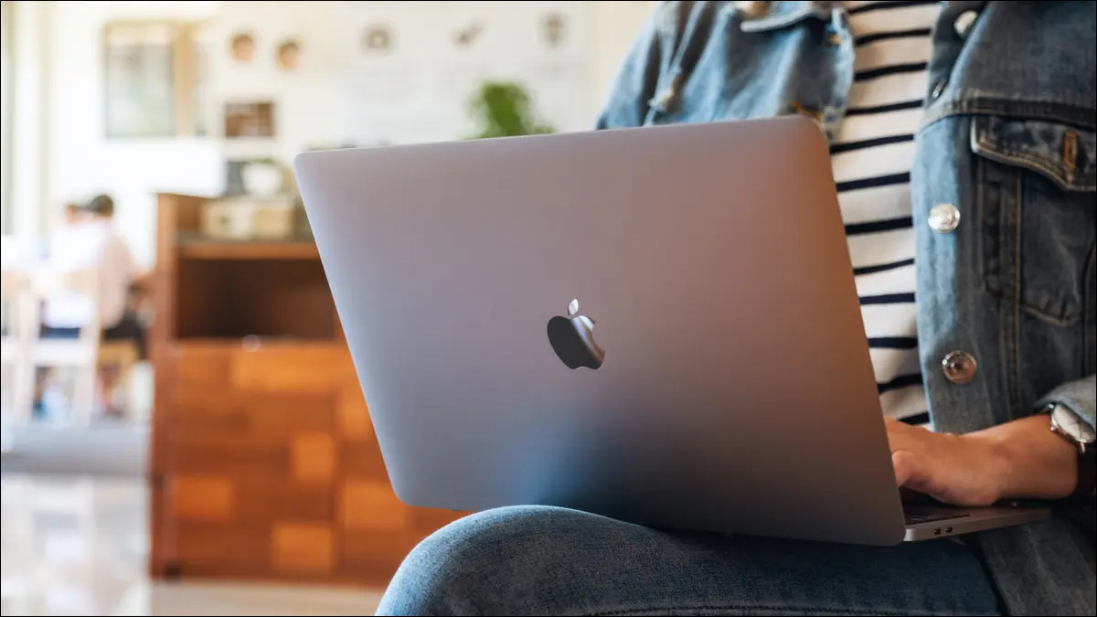 Person, die in einem Café ein MacBook auf dem Schoß verwendet