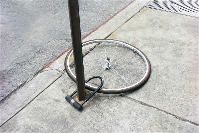 Uma única roda de bicicleta presa a um poste com uma trava de bicicleta, o resto da bicicleta presumivelmente roubado.