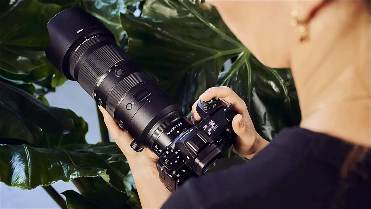 Nikon Nikkor 렌즈로 미러리스 카메라를 들고 있는 사람