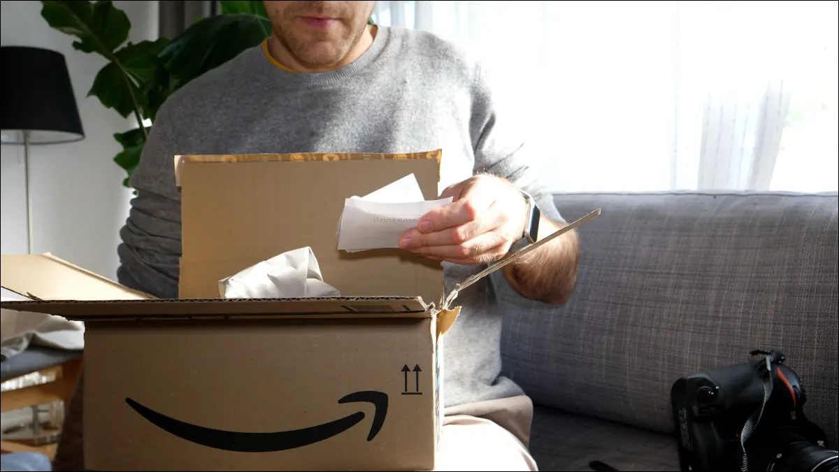 ผู้ชายกำลังเปิดแพ็คเกจ Amazon และอ่านสลิปการสั่งซื้อ