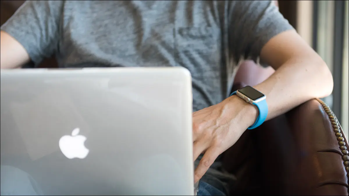 Uomo che usa un MacBook mentre indossa un Apple Watch