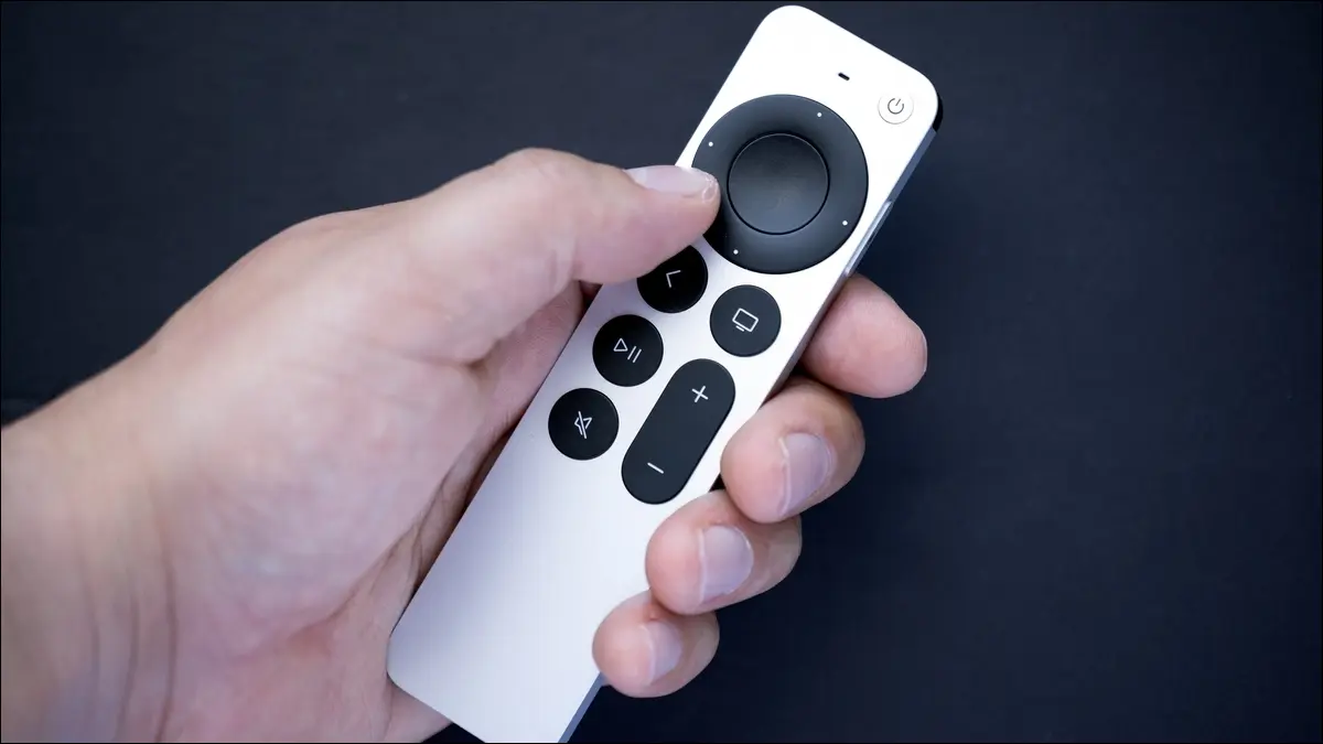 Eine silberne Apple TV-Fernbedienung in der Hand einer Person.