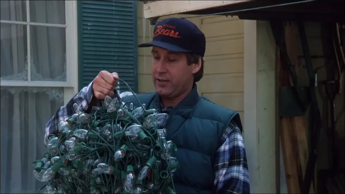 Un homme tient une boule de lumières de Noël enchevêtrées.