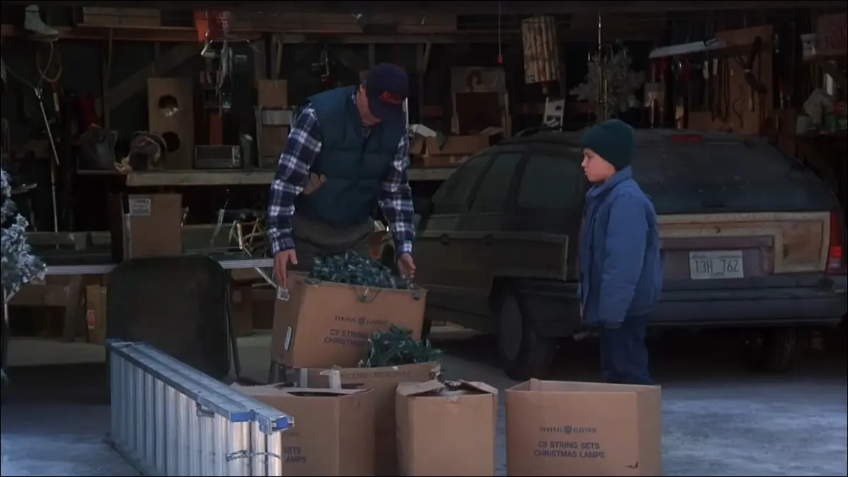 Un homme regarde des boîtes de lumières de Noël emmêlées avec ce fils.