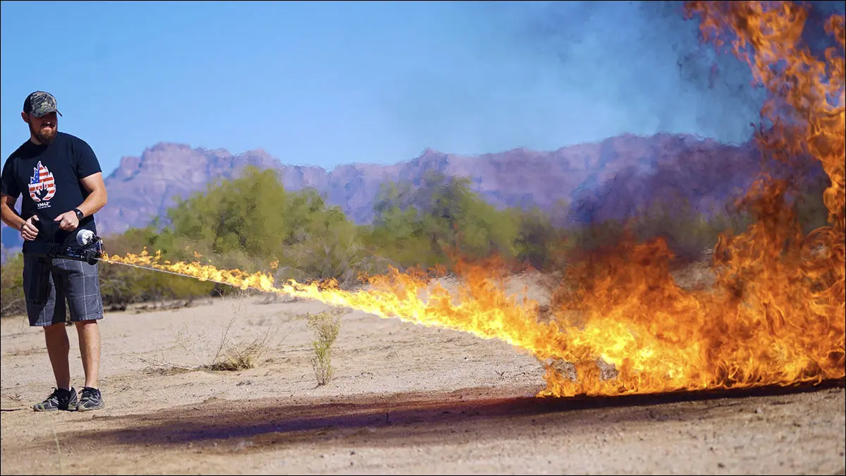 Un hombre usando un lanzallamas en el desierto.