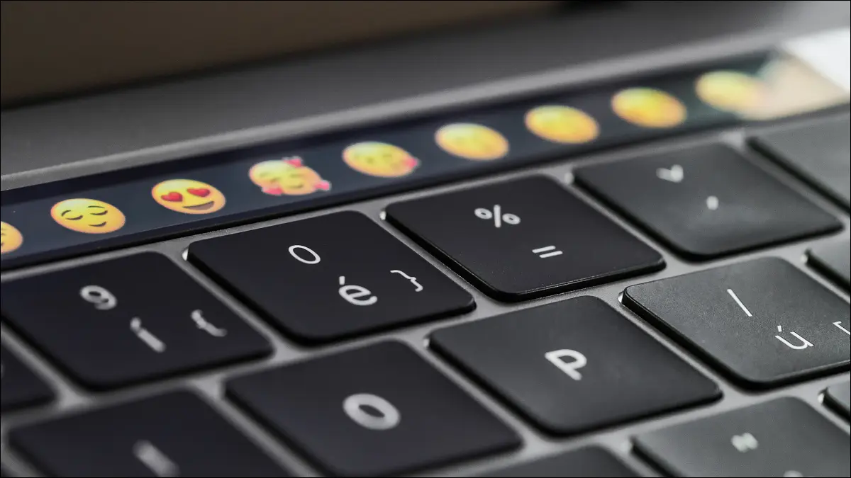 Tampilan close-up papan ketik MacBook Pro dengan Touch Bar menampilkan emoji dalam fokus.