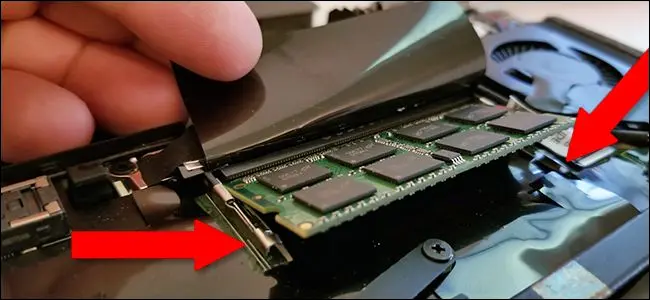 拉动笔记本电脑 RAM 模块两侧的卡舌将其松开，然后轻轻拉动杆将其取下。