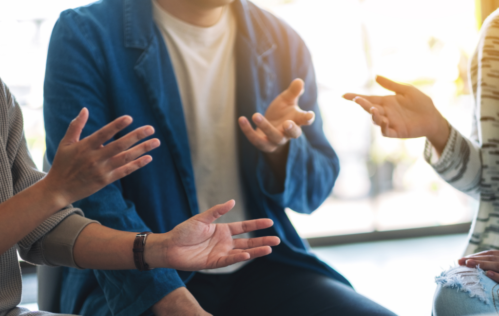 Gros plan de personnes faisant des gestes avec leurs mains pendant une conversation.